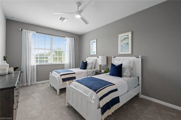 Bedroom featuring visible vents, baseboards, ceiling fan, and light carpet