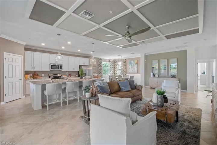 Living room with visible vents, light tile patterned floors, ornamental molding, ceiling fan, and coffered ceiling