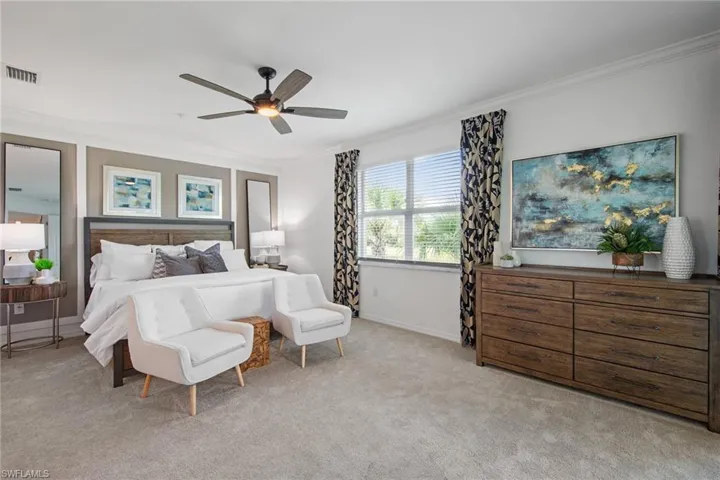 Bedroom featuring visible vents, baseboards, ornamental molding, ceiling fan, and light colored carpet
