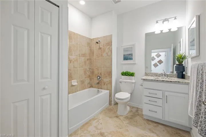 Bathroom with a closet, baseboards, washtub / shower combination, toilet, and vanity