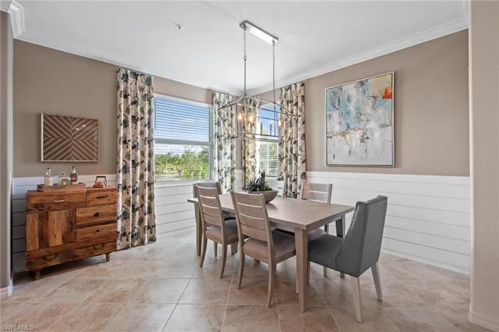 Dining area with an inviting chandelier, wood walls, crown molding, and a wainscoted wall