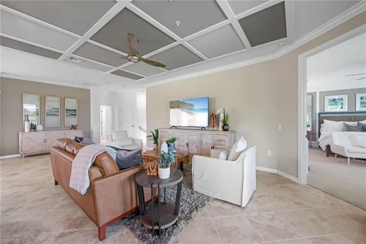 Living room with visible vents, ornamental molding, coffered ceiling, and ceiling fan