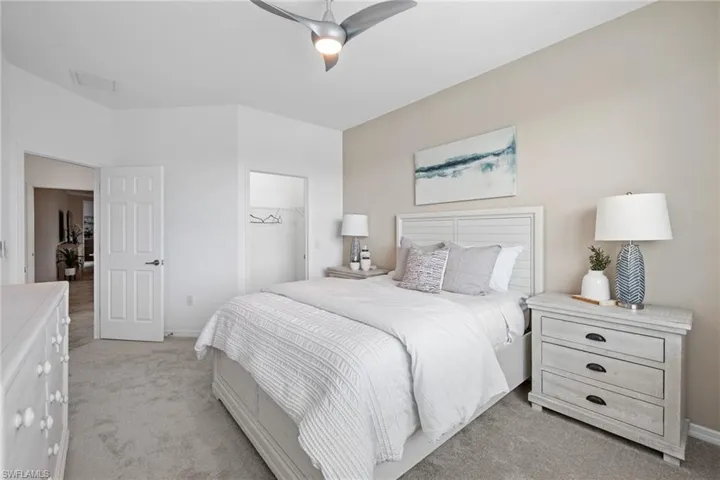 Bedroom featuring a closet, baseboards, a spacious closet, a ceiling fan, and light colored carpet