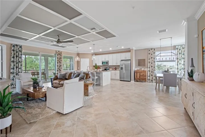 Living area with coffered ceiling, a healthy amount of sunlight, ceiling fan with notable chandelier, and visible vents
