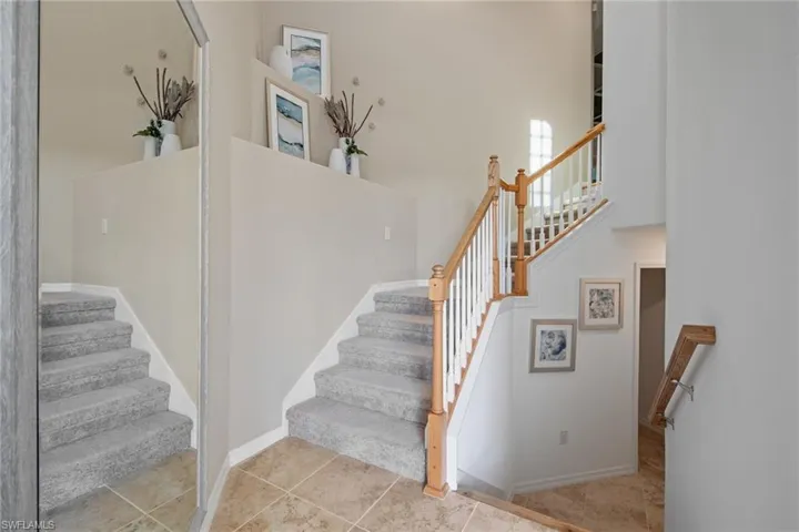 Stairway with tile patterned flooring, a towering ceiling, and baseboards
