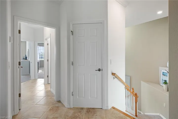 Hall with an upstairs landing, baseboards, and light tile patterned floors