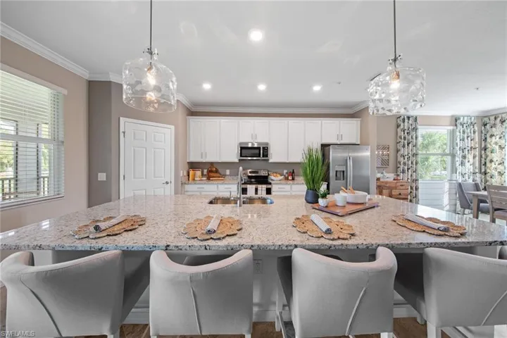 Kitchen with a sink, appliances with stainless steel finishes, crown molding, white cabinetry, and a spacious island