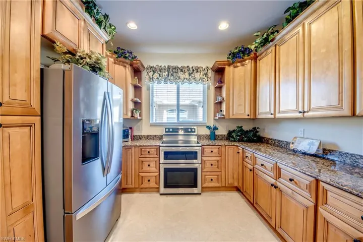 Kitchen featuring appliances with stainless steel finishes, open shelves, stone counters, and recessed lighting