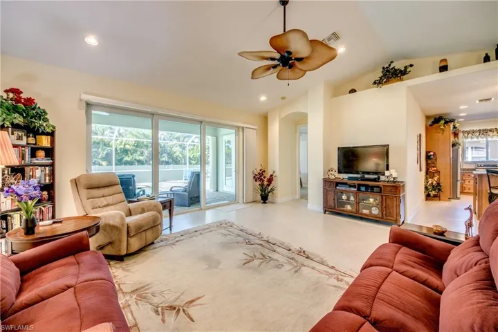 Living area with a ceiling fan, arched walkways, vaulted ceiling, and recessed lighting