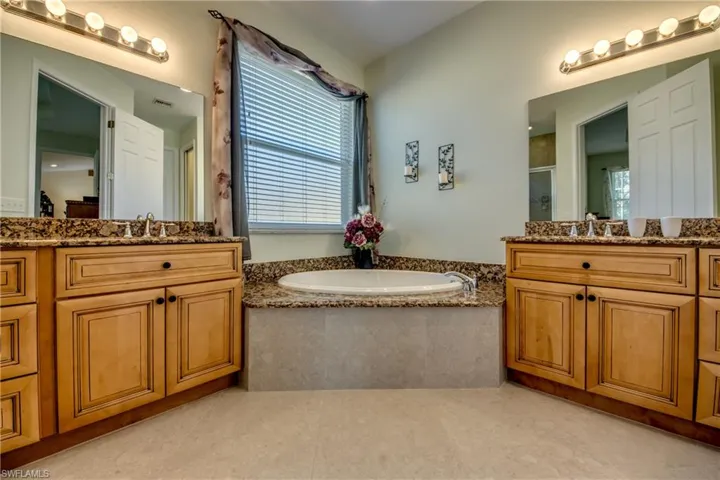 Full bath featuring a stall shower, two vanities, and a bath