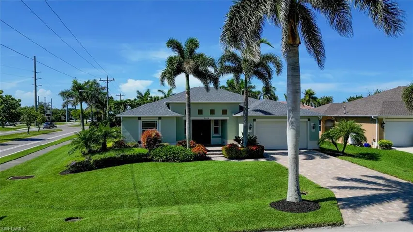 Ranch-style home featuring stucco siding, an attached garage, a front lawn, and decorative driveway