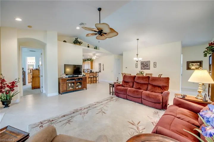 Living area featuring ceiling fan, a chandelier, vaulted ceiling, and arched walkways