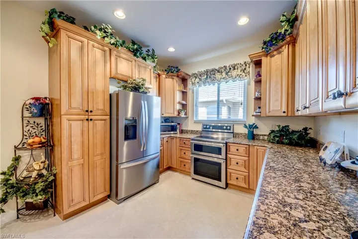 Kitchen with stainless steel appliances, open shelves, light stone countertops, recessed lighting, and light brown cabinets
