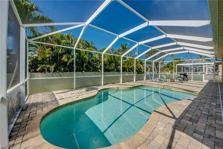 View of pool with a patio area and glass enclosure