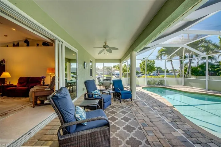 View of patio with a ceiling fan, an outdoor pool, and glass enclosure