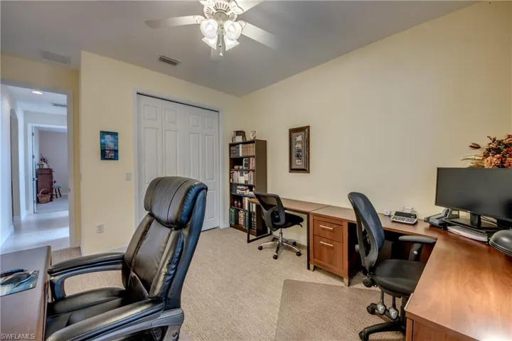 Office with a ceiling fan and light colored carpet