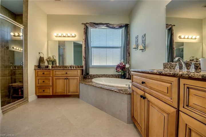 Full bath featuring a stall shower, two vanities, and a bath