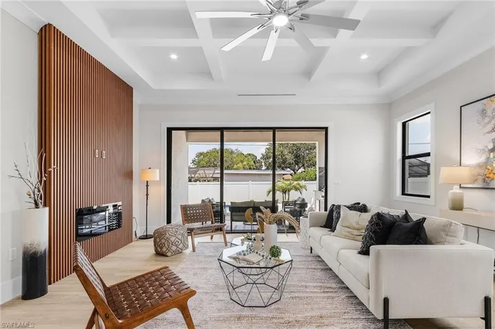 Living room featuring coffered ceiling, light wood-style floors, a ceiling fan, beam ceiling, and recessed lighting