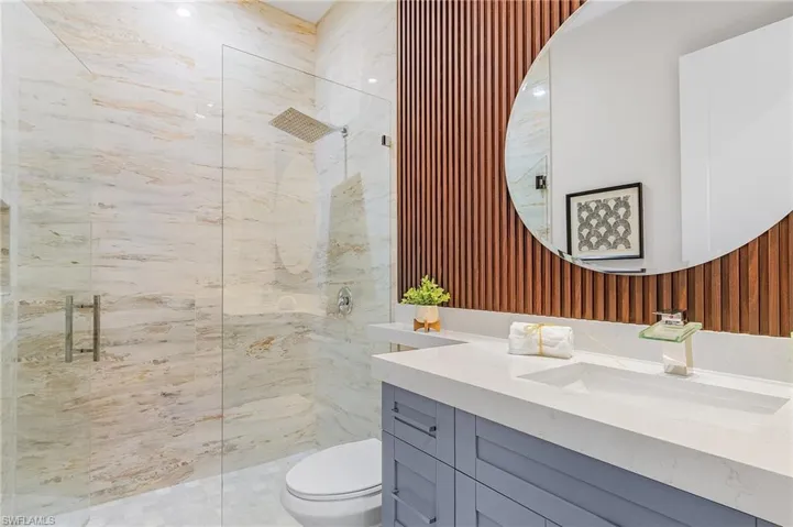 Bathroom featuring vanity, tiled shower, and toilet