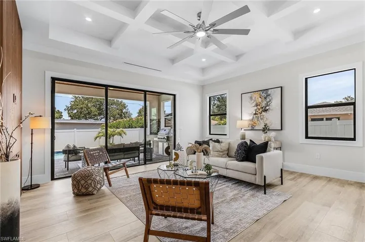 Living room with coffered ceiling, a ceiling fan, recessed lighting, beamed ceiling, and light wood finished floors
