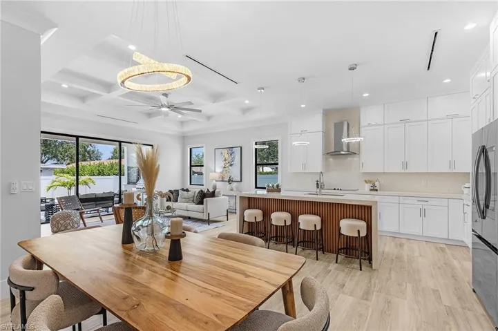 Dining room featuring plenty of natural light, coffered ceiling, light wood-type flooring, recessed lighting, and ceiling fan