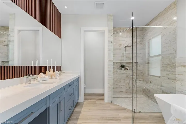 Full bath featuring double vanity, a shower stall, a soaking tub, and toilet