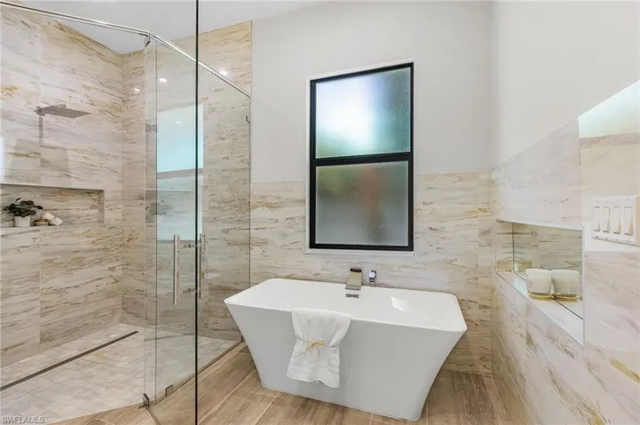 Full bathroom with tile walls, tiled shower, and a freestanding tub