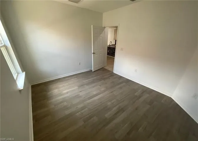 This room features light-colored walls, a window with a white sill, and wood-look flooring
