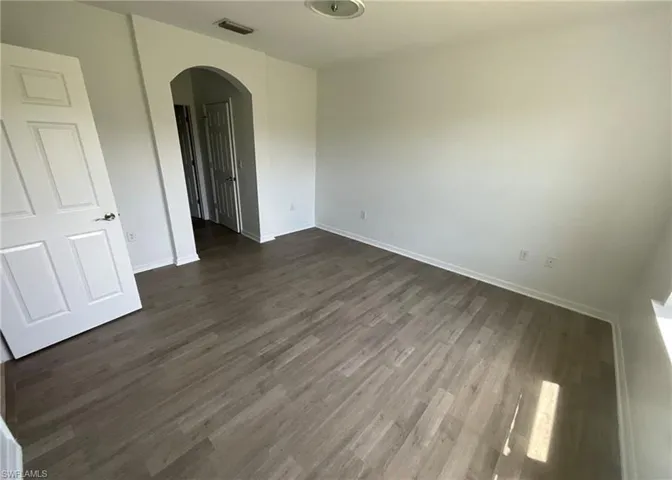 This room features light-colored walls, wood-style flooring, and a white interior door