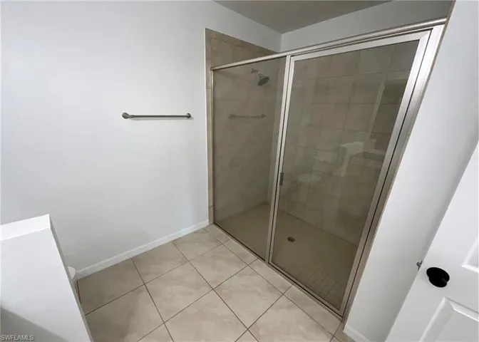 Shower with glass enclosure, tiled walls, and tiled floor