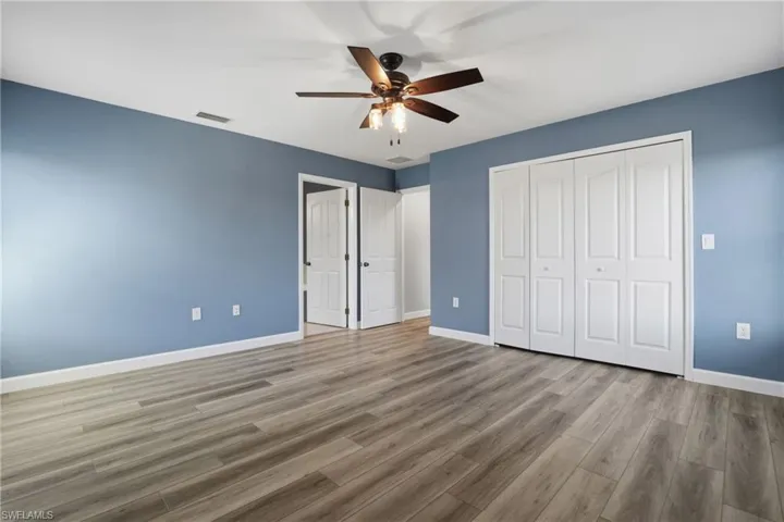 Unfurnished bedroom with a ceiling fan, wood finished floors, and a closet