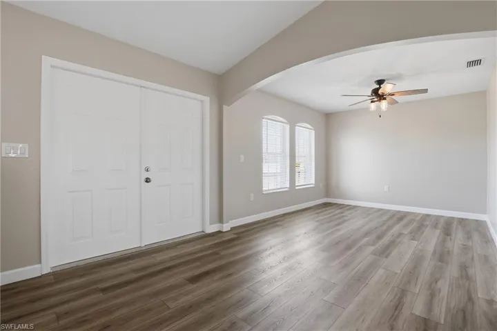 Entryway with a ceiling fan, arched walkways, and dark wood finished floors