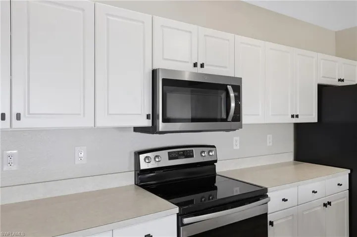 Kitchen featuring stainless steel appliances, white cabinets, and light countertops