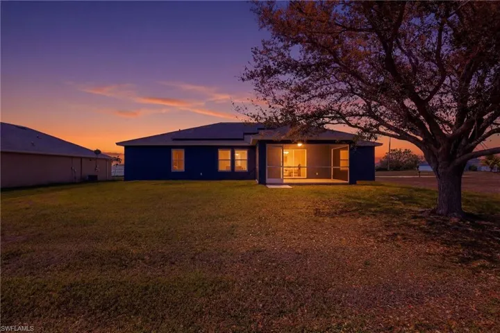 Back of house with solar panels, a yard, a patio, and stucco siding