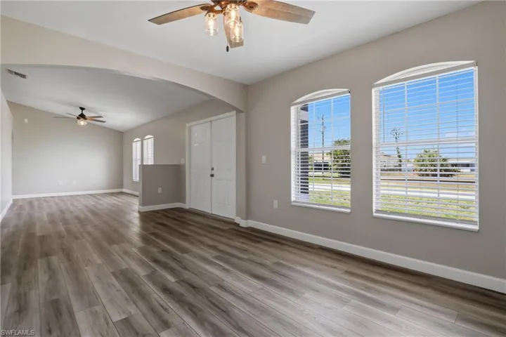 Unfurnished room with ceiling fan, light wood-type flooring, and arched walkways