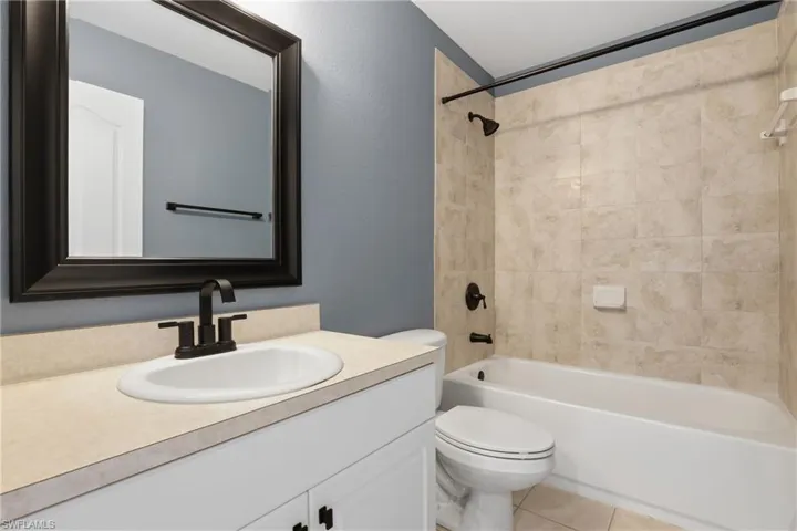 Full bathroom with vanity, shower / washtub combination, light tile patterned flooring, and a textured wall