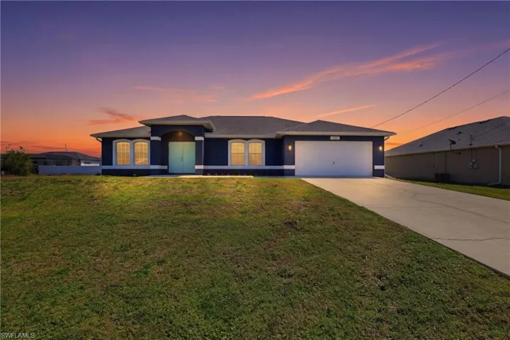 View of front facade with a yard, concrete driveway, an attached garage, and stucco siding