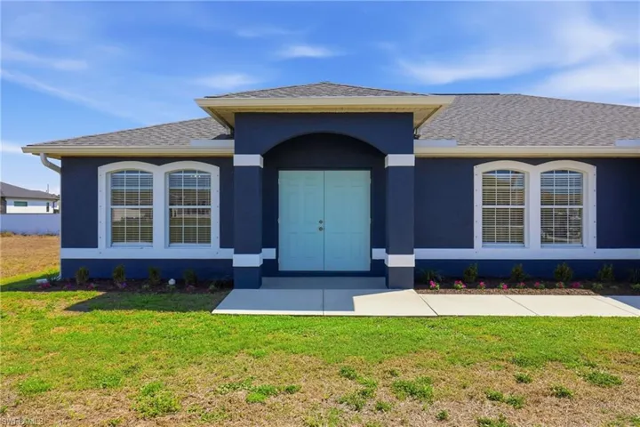 Entrance to property with stucco siding, a lawn, and roof with shingles