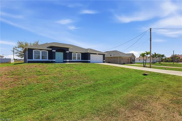 Ranch-style house featuring driveway, a garage, a front yard, and stucco siding
