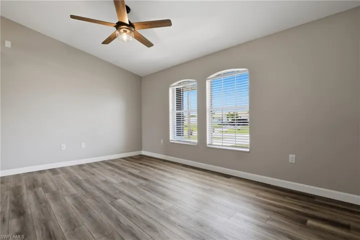 Empty room with vaulted ceiling, light wood-style floors, and a ceiling fan
