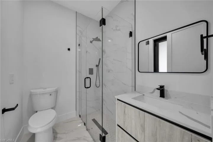 Bathroom with a marble finish shower, vanity, and light marble finish floors