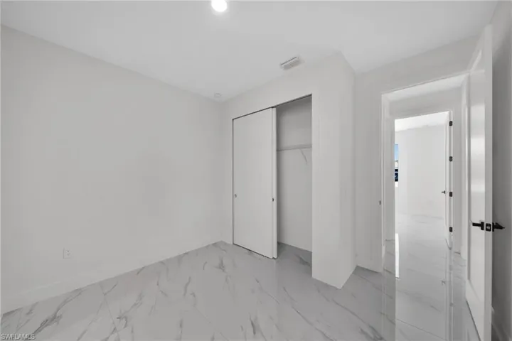 Unfurnished bedroom with light marble finish flooring and a closet