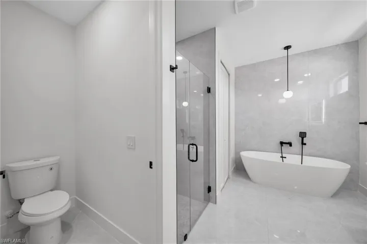 Full bathroom with a stall shower, a soaking tub, and tile walls
