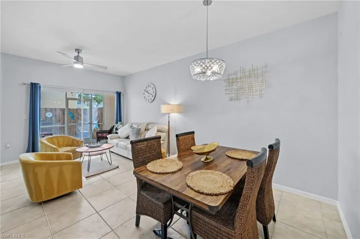 Bright living and dining area featuring tiled flooring, a decorative light fixture, and a ceiling fan