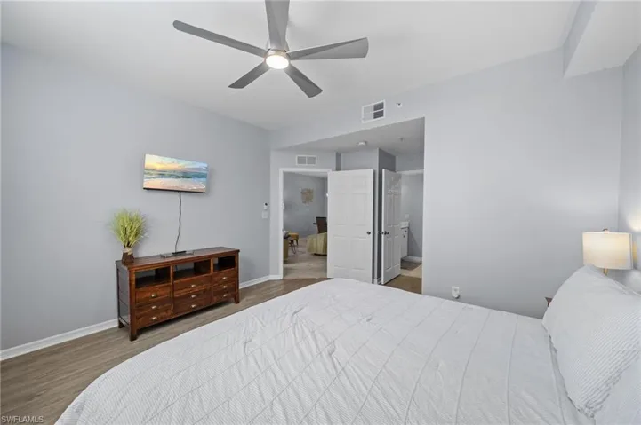 This room features light-colored walls, wood-look flooring, and a ceiling fan with integrated lighting