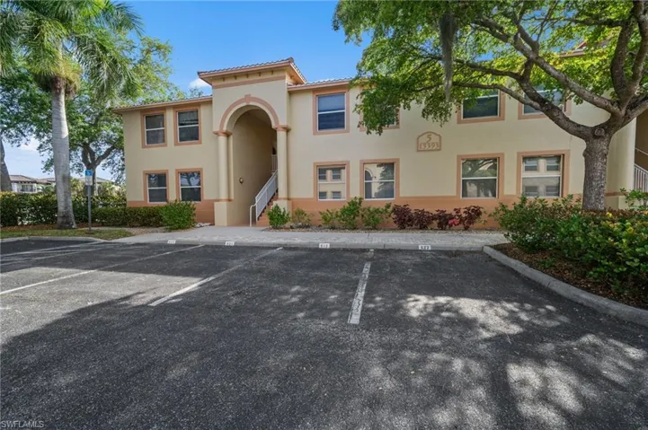 The property features a two-story exterior with a tiled roof, stucco finish, and an arched entrance, surrounded by mature trees and landscaping