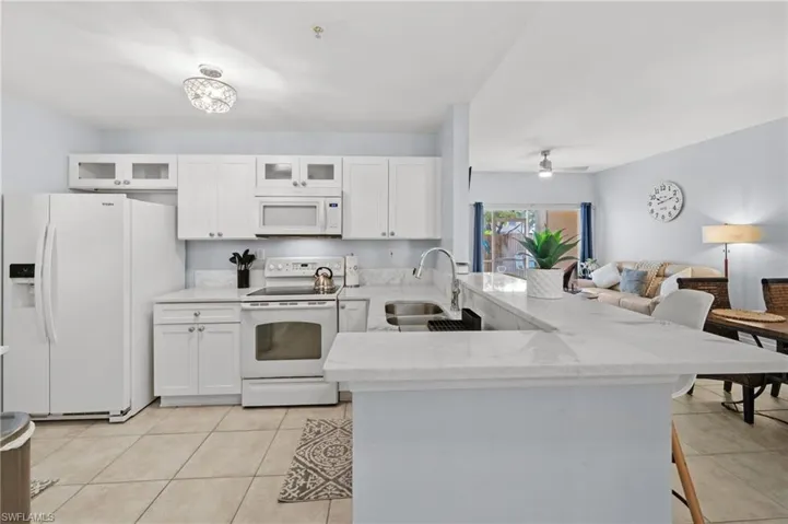 The kitchen features white cabinetry, white appliances, and light-colored countertops