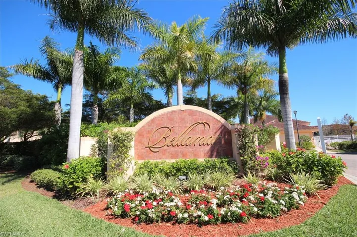 The property is situated within a community featuring an ornate entrance sign set amidst lush landscaping with palm trees and vibrant flowers