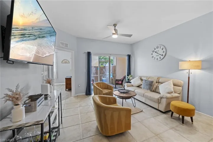 The living area features tile flooring, a ceiling fan, and sliding glass doors leading to an outdoor space