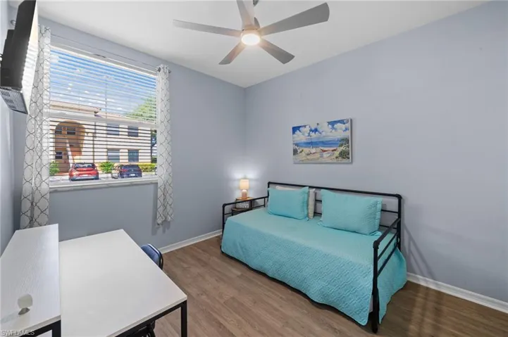 This inviting room features wood-look flooring, light blue walls, and a window with blinds and patterned curtains